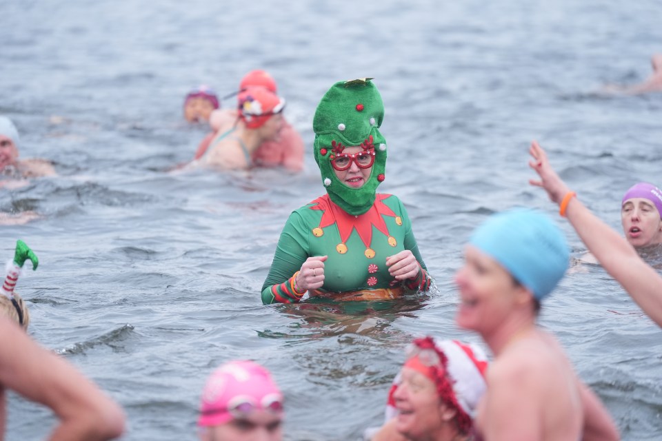 A woman in a Christmas elf costume participates in a winter swimming race.