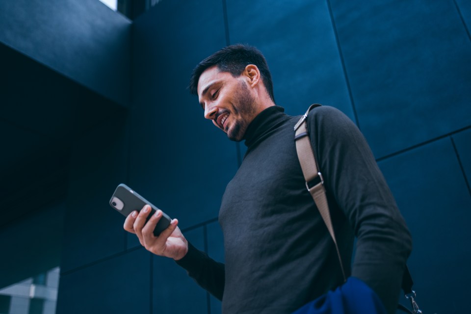 Smiling businessman reading a text message on his phone.