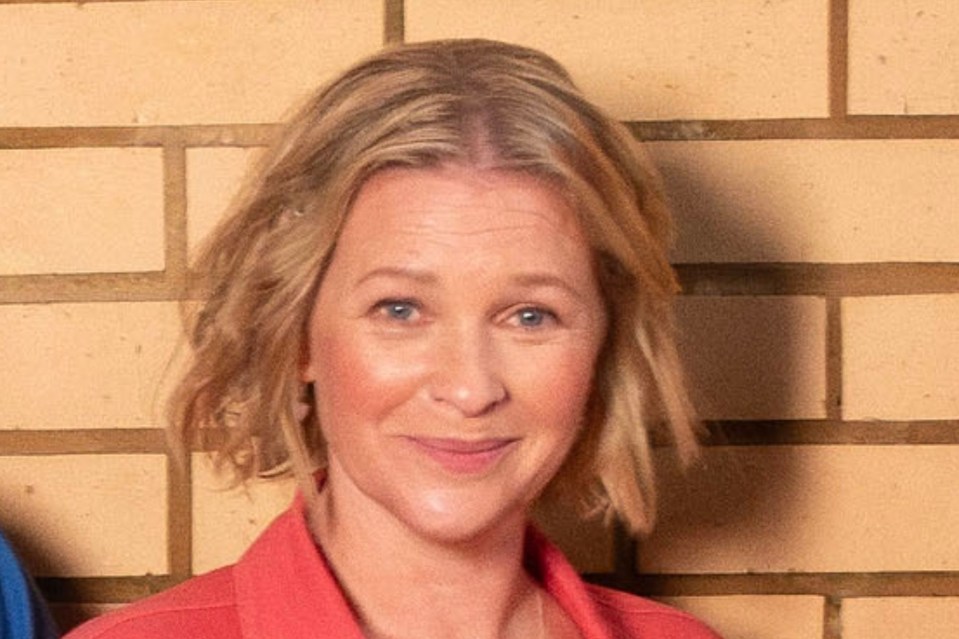 Headshot of a woman with blonde hair wearing a coral shirt.