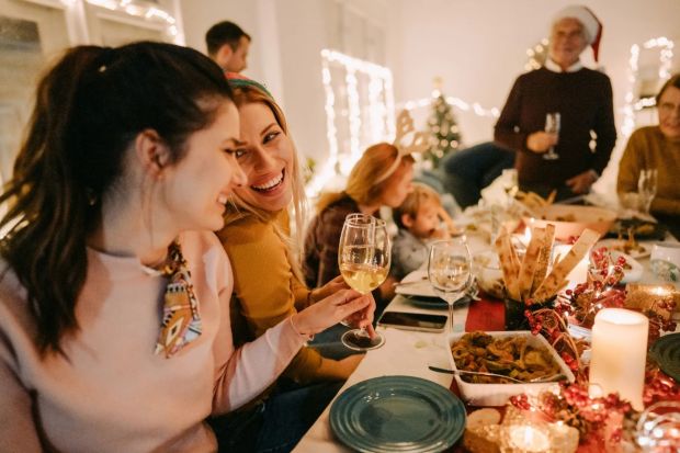 Two women smiling at a Christmas dinner table.