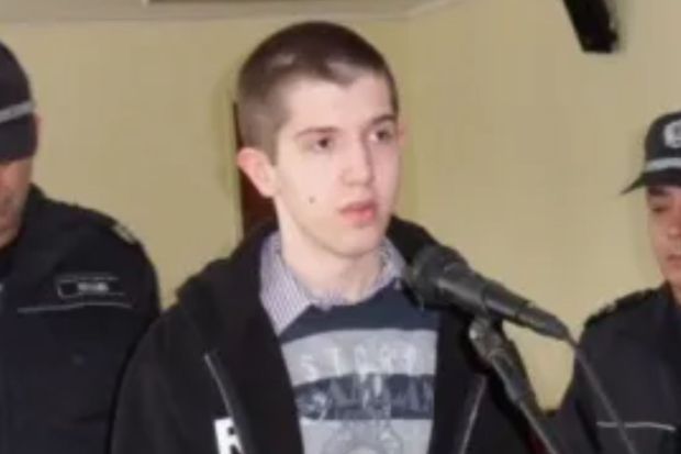 A young man speaks at a microphone flanked by police officers.