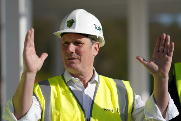 Man in hard hat and safety vest gesturing with both hands.