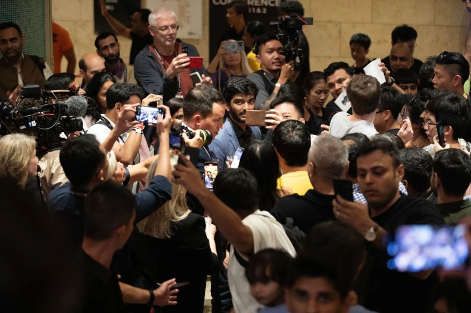 Gukesh surrounded by fans and press.