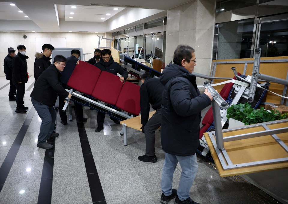 Officials removing furniture barricading the doors of the National Assembly building.