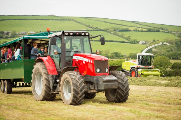 A tractor pulling a trailer full of people on a farm.