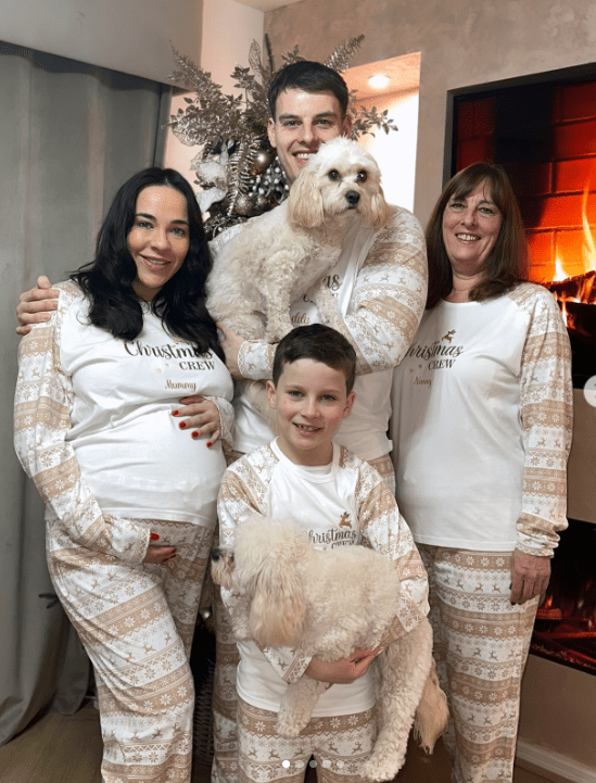 Family in matching Christmas pajamas with two dogs.