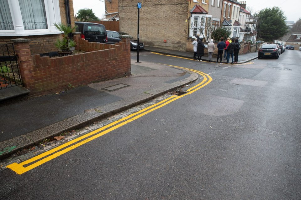 Neighbours from the area can be seen on the pavement near the double yellow lines