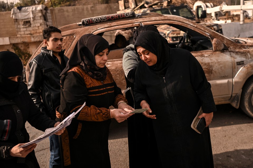 People search documents, to find any information on their missing relatives, at the Mazzeh military airport