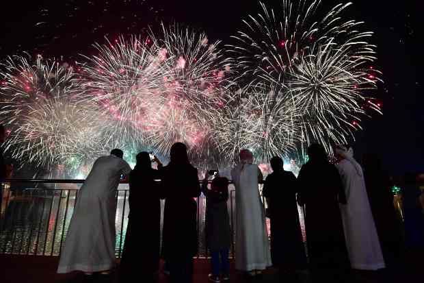 People watching fireworks over water.