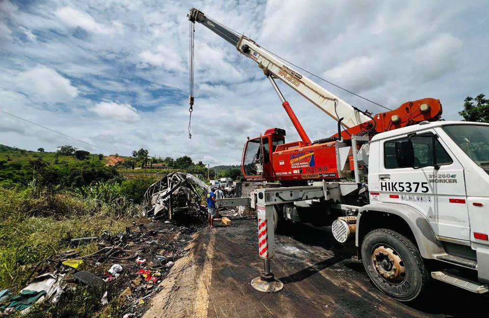 A crane works to move the bus from the side of the road