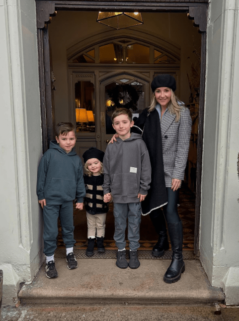 A woman and her three children stand in a doorway.