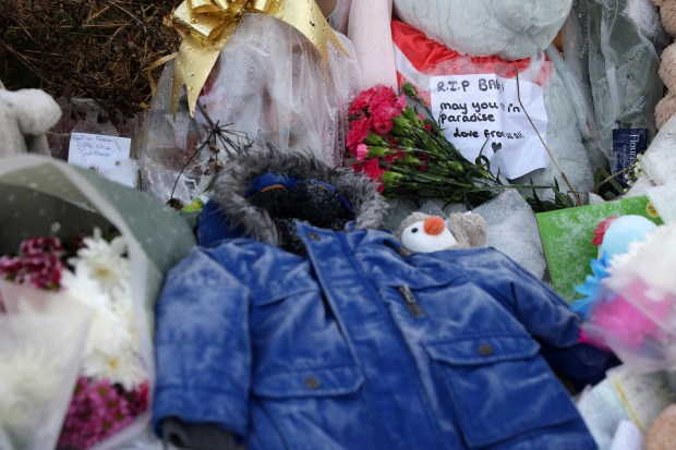 Floral tributes and a child's coat at a memorial.