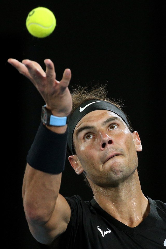 Rafael Nadal tossing a tennis ball before serving.