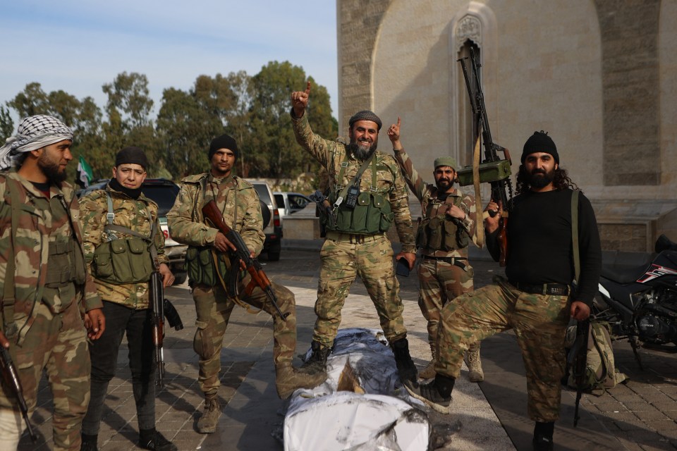 Rebel fighters pose for a picture outside the mausoleum of Syria’s late president Hafez al-Assad in the family’s ancestral village of Qardaha