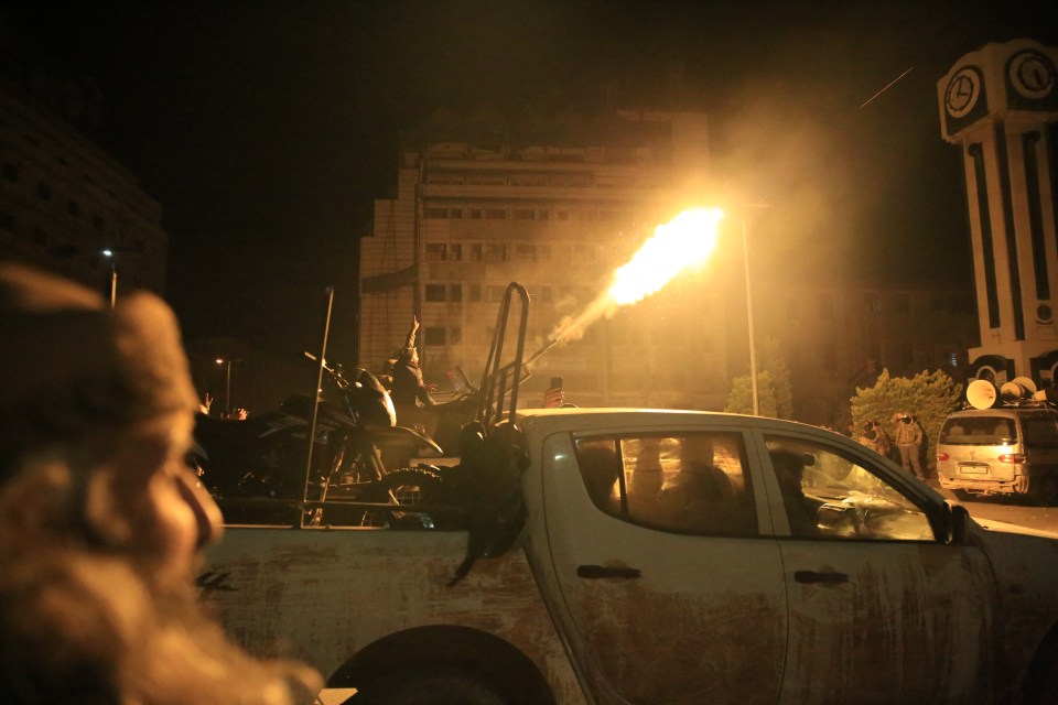 Rebel forces shoot in the air as they parade in their vehicles through the streets of Homs