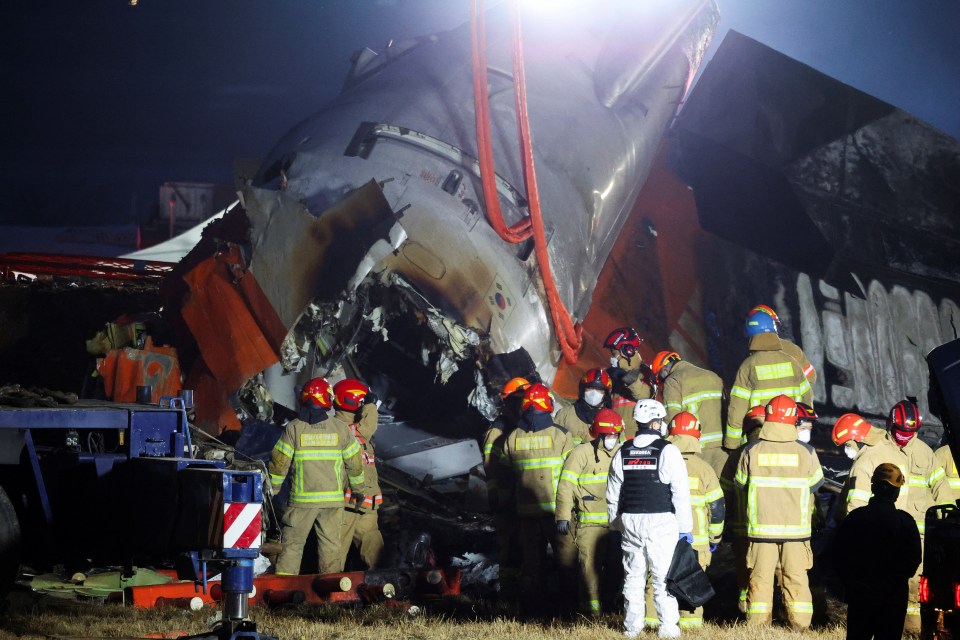 Rescuers work on the burnt wreckage of the aircraft