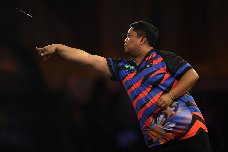 Sandro Eric Sosing of the Philippines throws a dart during a darts match.