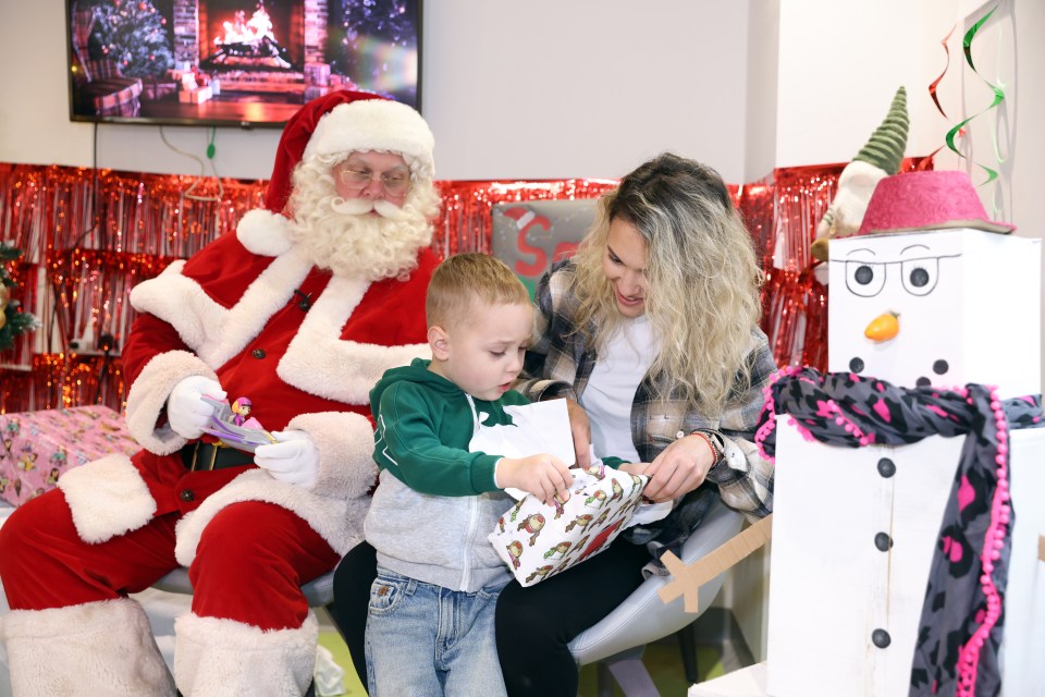 Santa Claus gives a Christmas present to a young boy at a hospital.