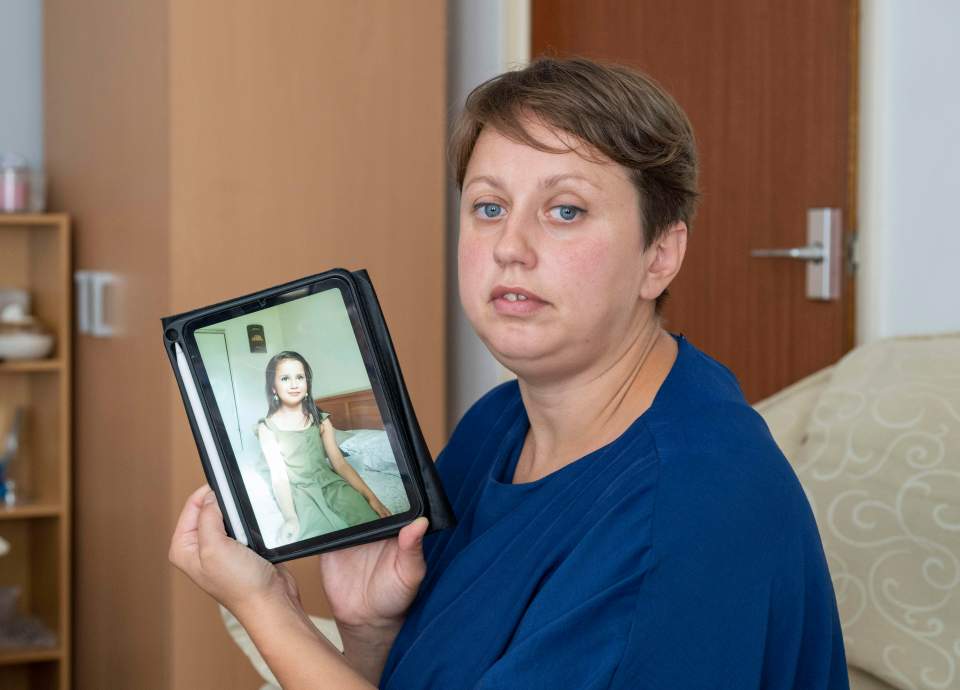 Woman holding tablet displaying photo of young girl.