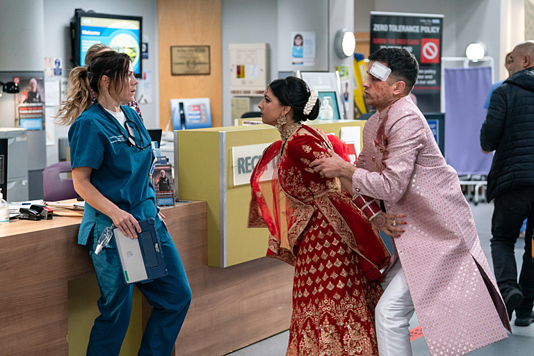 A scene from BBC Casualty showing a nurse attending to a bride and groom who appear injured.