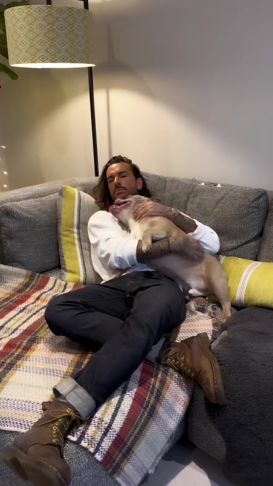 Pete Wicks cuddling his dog on a sofa.