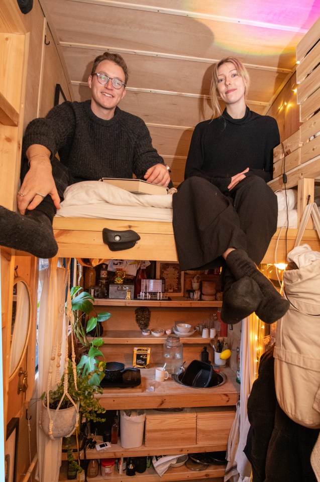 A couple sits on a loft bed in their converted shipping container home in London.