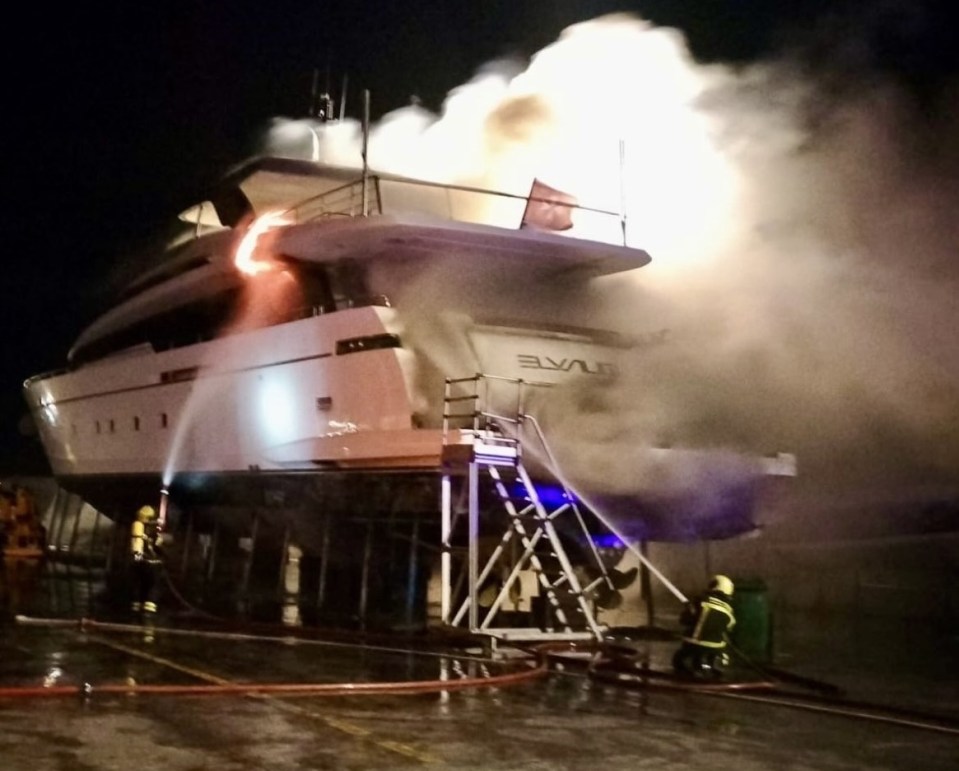 Firefighters extinguishing a fire on a large yacht.