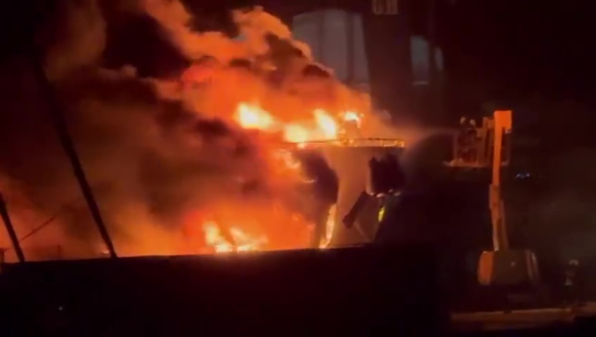 A superyacht engulfed in flames in a port.