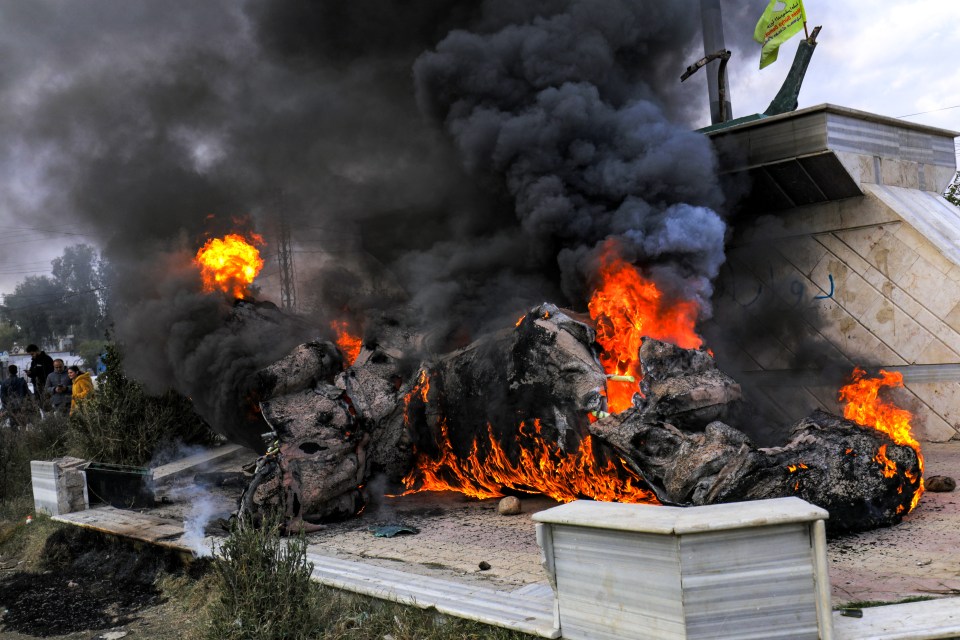 Syrian Kurds next to the destroyed statue of Basel al-Assad, the late elder brother of Syria’s President Bashar al-Assad