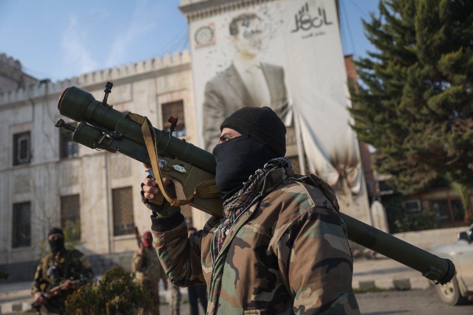 A Syrian opposition fighter holds a rocket launcher in front of the provincial government office