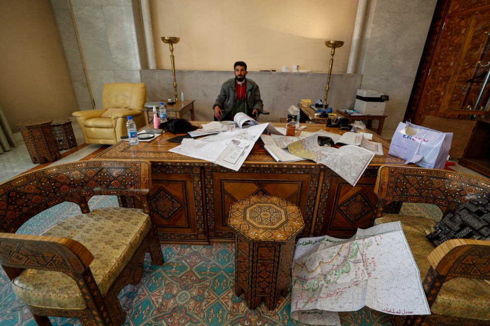 A Syrian opposition fighter sits at a desk inside an office at the palace