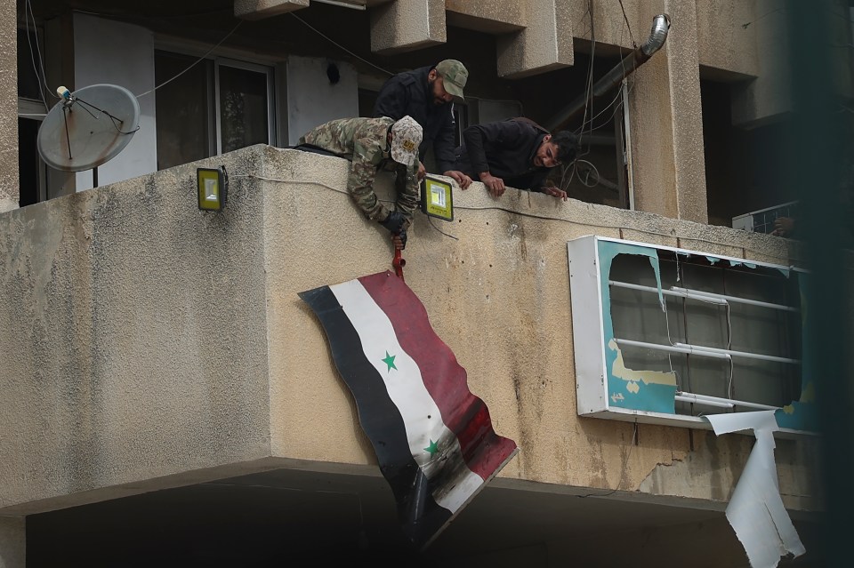 Syrian opposition fighters remove a government flag from an official building in Salamiyah, east of Hama