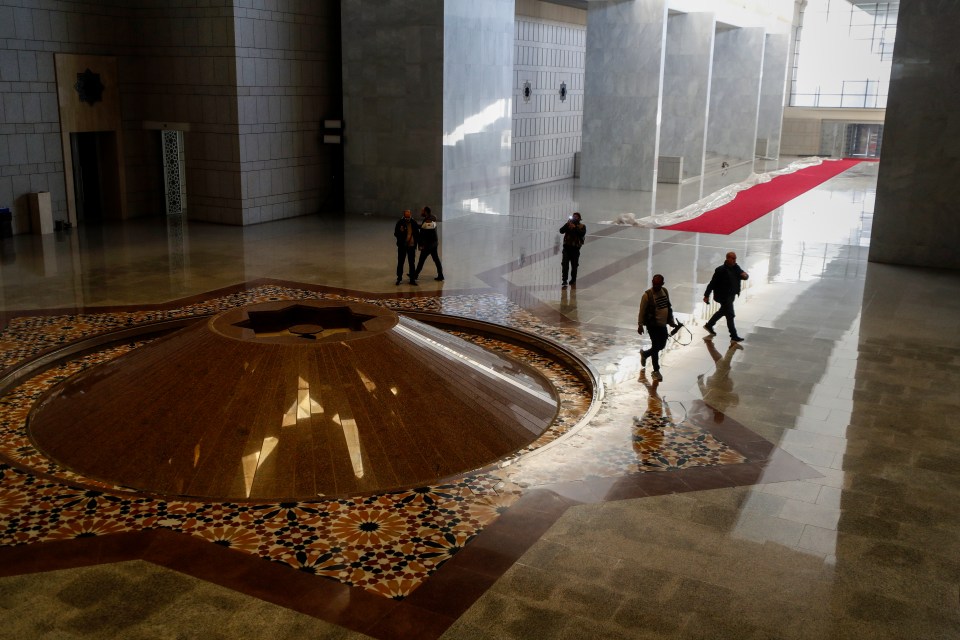 Syrian opposition fighters walk inside a grand hall in the Presidential Palace