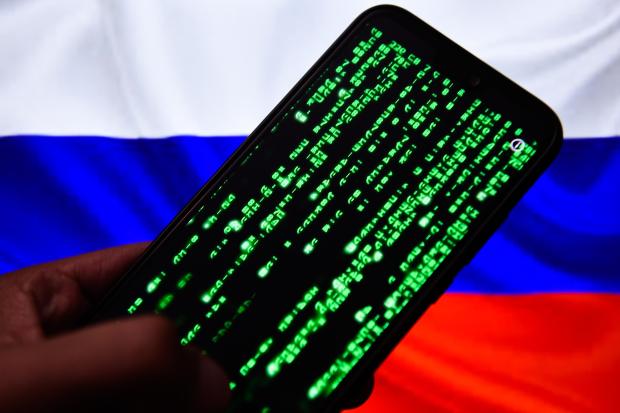 Smartphone displaying matrix-style code against a Russian flag.