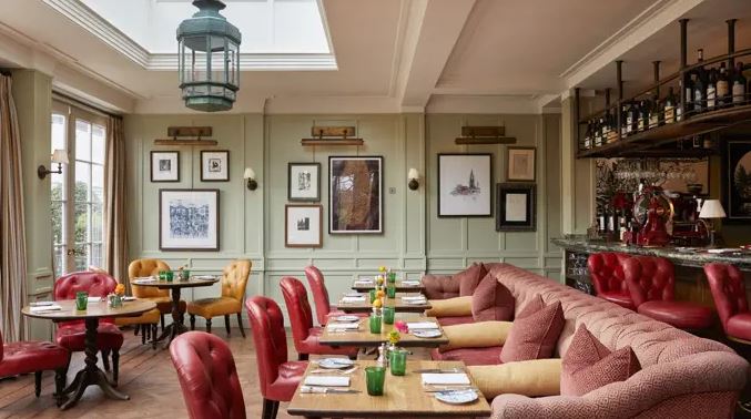 Interior of a UK hotel restaurant with red seating and a long sofa.