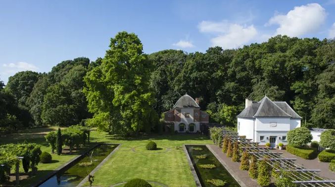 Aerial view of a UK hotel in a national park, featuring two buildings and formal gardens with reflecting pools.