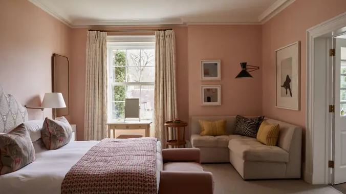 Hotel room with a bed, seating area, and large window.