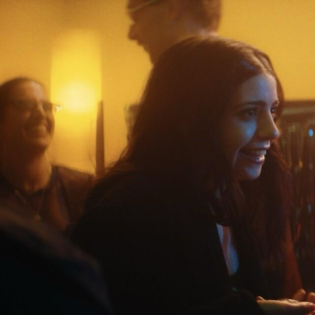 Woman smiling in dimly lit room.