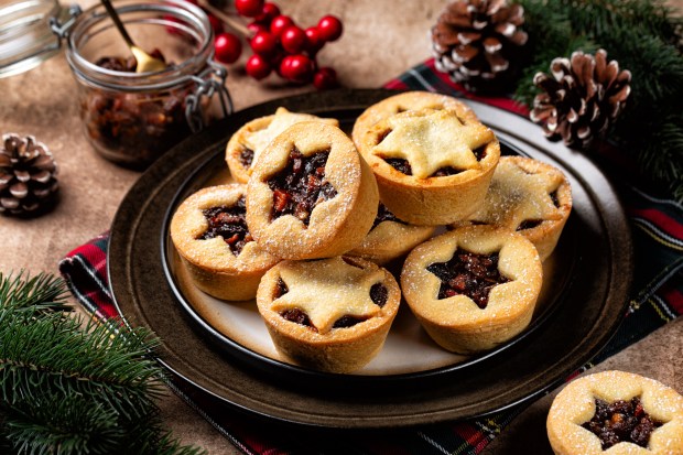 A plate of traditional British mince pies, dusted with powdered sugar.