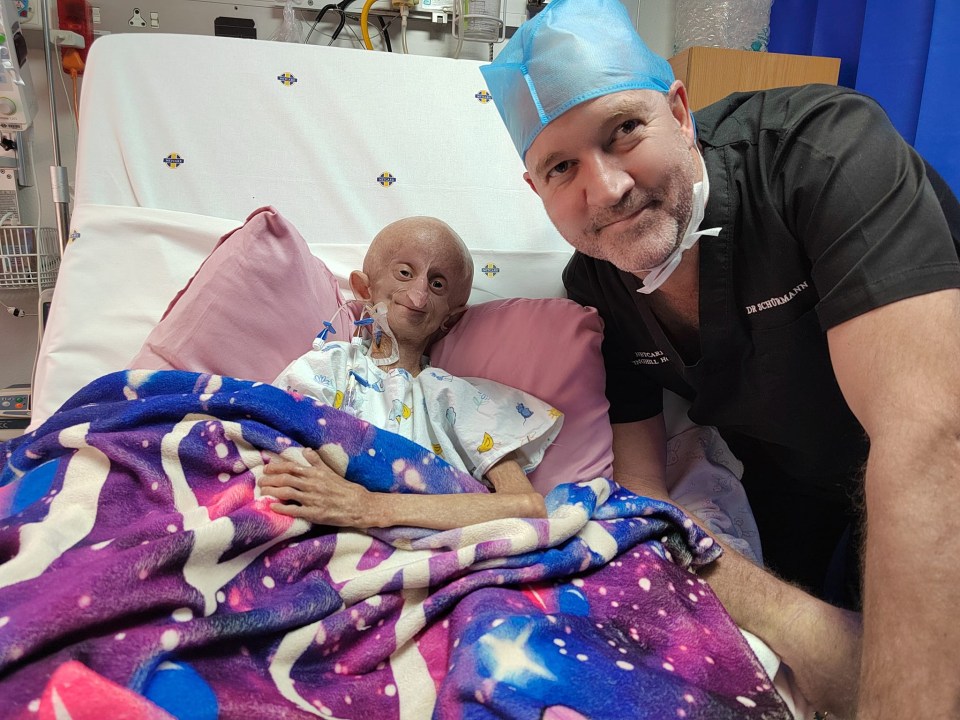 A surgeon with a young patient in a hospital bed.