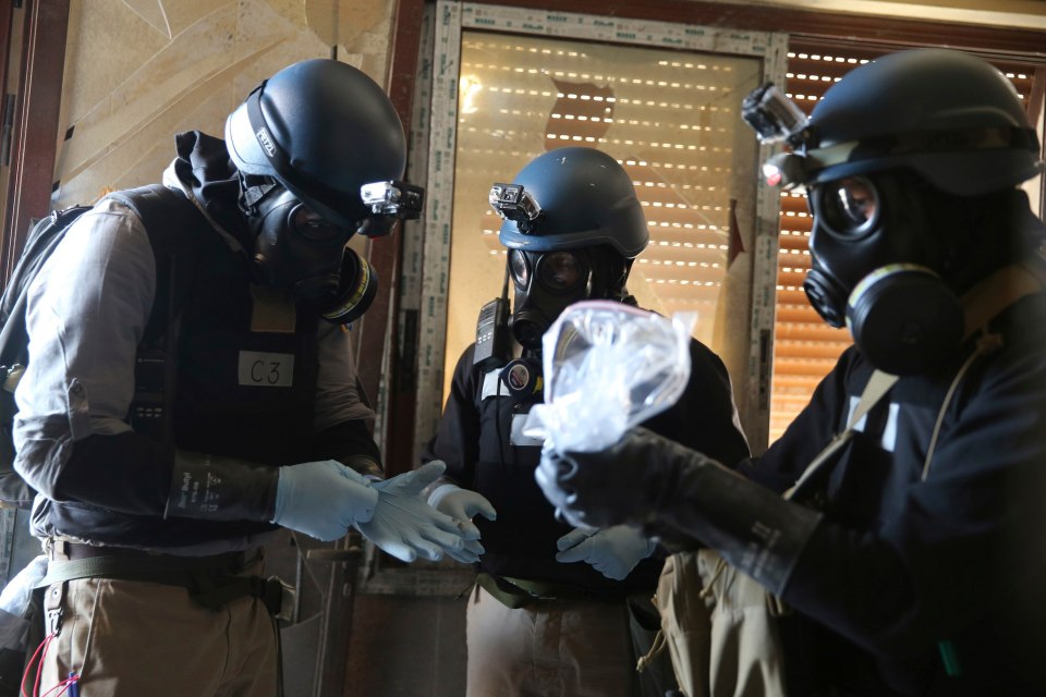 A U.N. chemical weapons expert, wearing a gas mask, holds a plastic bag containing samples from one of the sites of an alleged chemical weapons attack