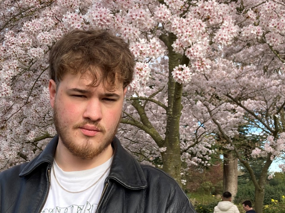 Photo of William Hewes in front of cherry blossoms.