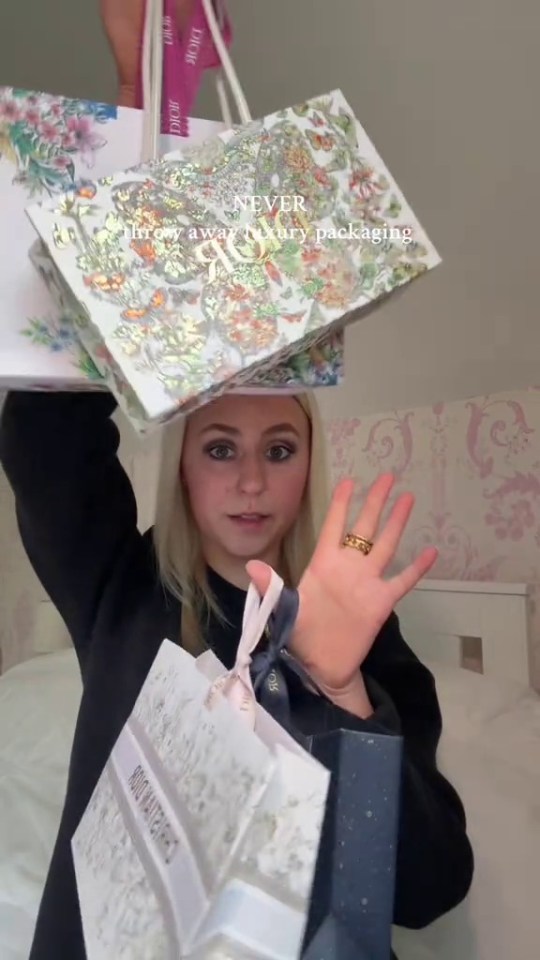 Woman holding up several luxury brand shopping bags, suggesting their resale value.