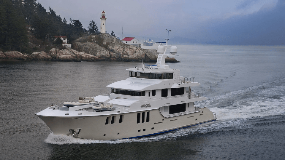 The Aurora, a luxury motor yacht, cruising past a lighthouse.