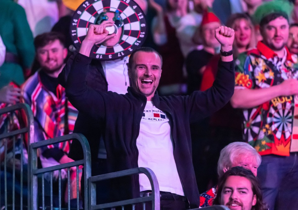 A jubilant darts fan celebrates in the audience.