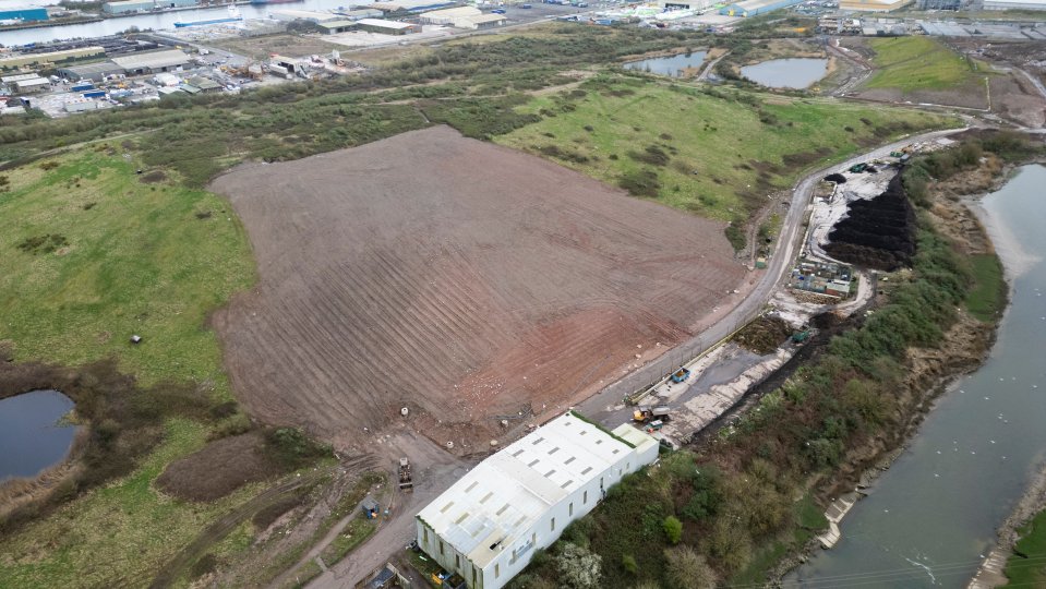 Aerial view of a landfill site with a large expanse of bare earth and a building.