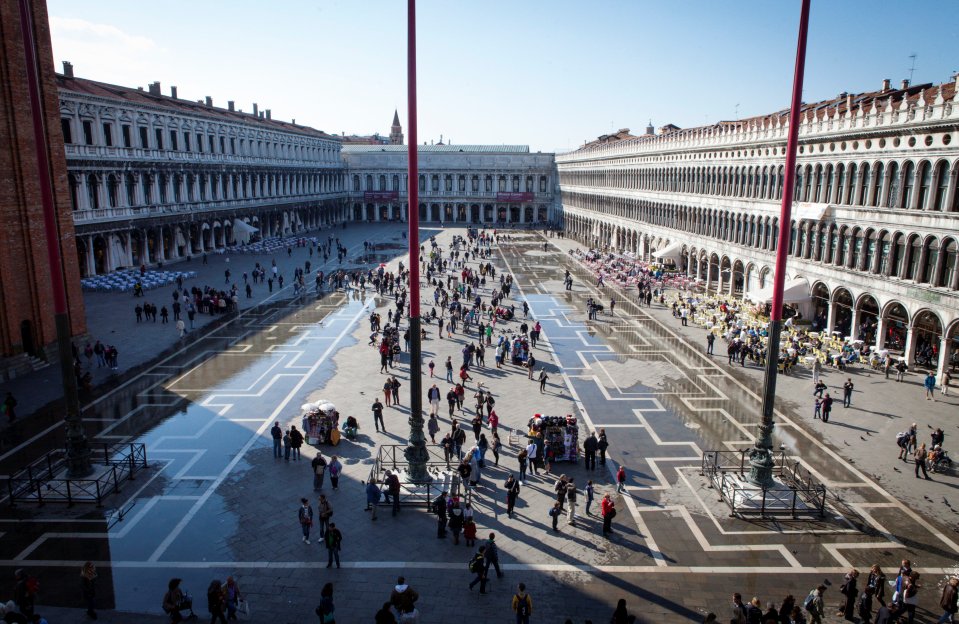 Aerial view of St. Mark's Square in Venice, Italy, with many people and flooded sections.