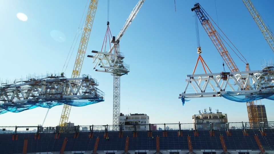 Construction of a stadium roof using large cranes.