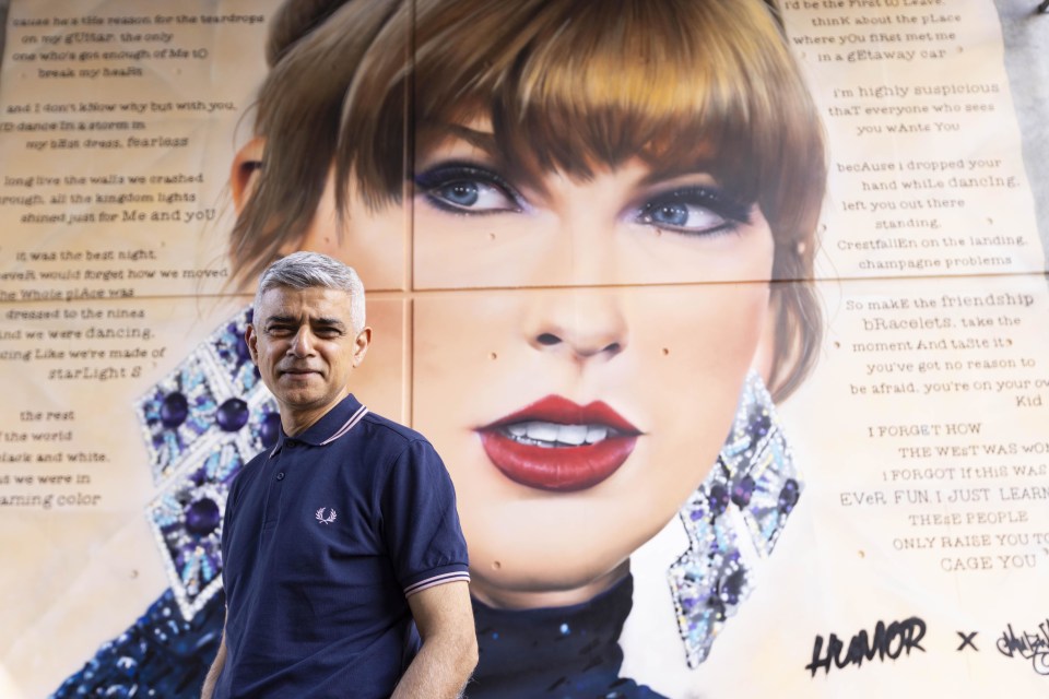 Mayor Sadiq Khan standing in front of a mural of Taylor Swift.