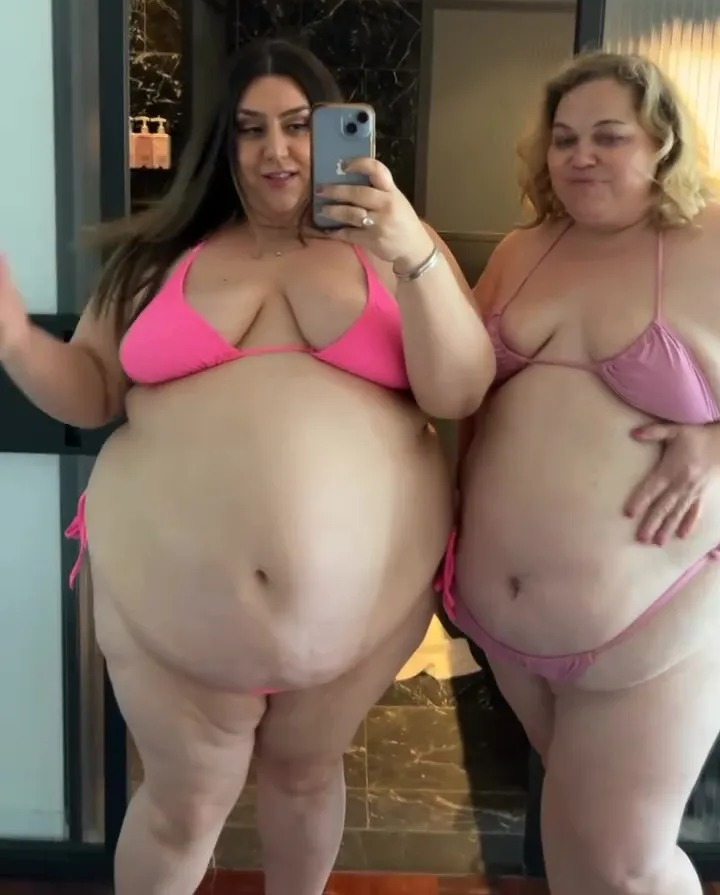 Two women in pink bikinis taking a selfie.